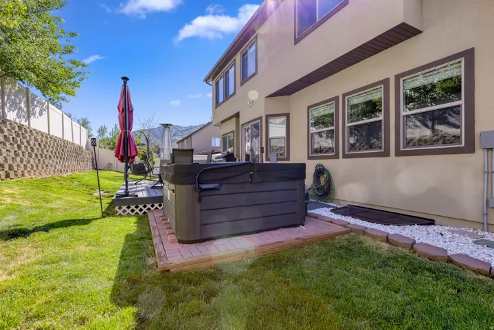 Expansive backyard featuring a built-in hot tub on a brick paver base, a multi-level deck with lattice skirting, and a manicured lawn