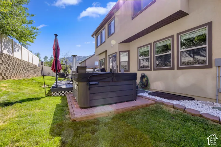 Expansive backyard featuring a built-in hot tub on a brick paver base, a multi-level deck with lattice skirting, and a manicured lawn