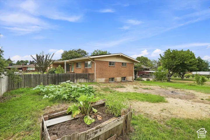 Brick exterior, fenced yard, raised garden bed, and mature landscaping