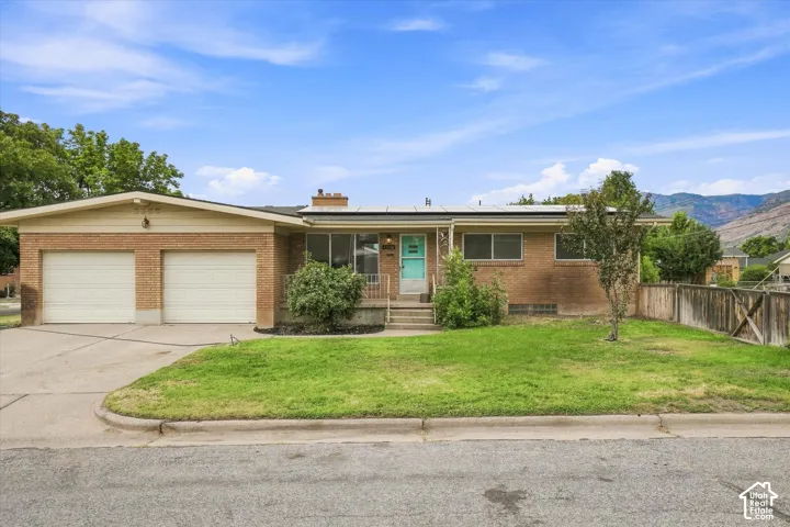Brick exterior with an attached two-car garage, front lawn, and established trees
