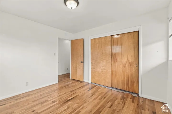 Hardwood flooring, light wood bi-fold closet doors, light wood interior door, and a flush mount ceiling light fixture