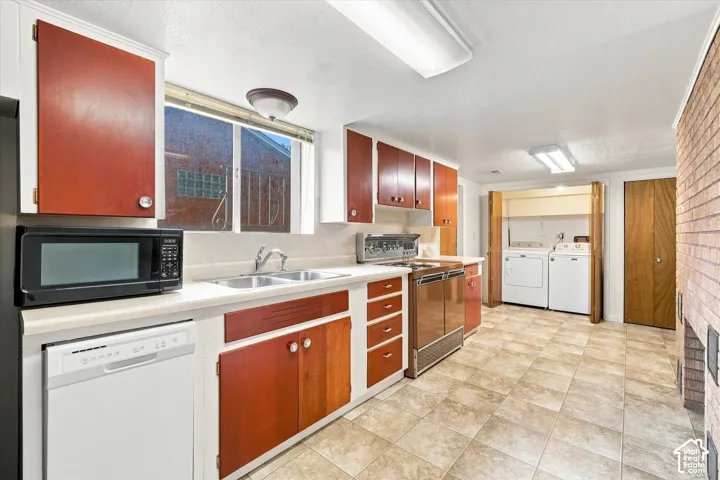 Basement kitchen with tile flooring, dual basin stainless steel sink, wood-finish cabinetry, and white countertops