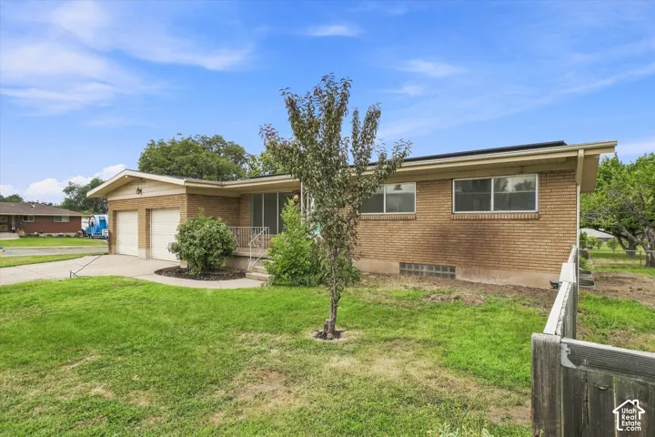 Brick exterior with a dual garage, concrete driveway, and mature landscaping