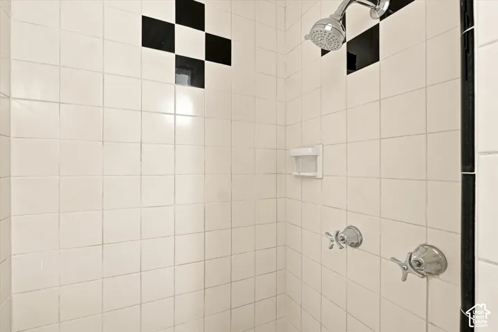 White square tile shower surround with black accent tiles and chrome fixtures