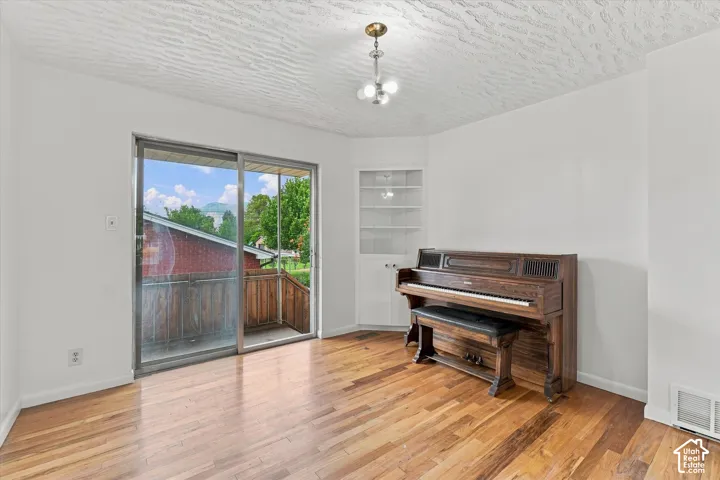 Hardwood flooring, sliding glass door, built-in shelving, white walls, and an overhead light fixture