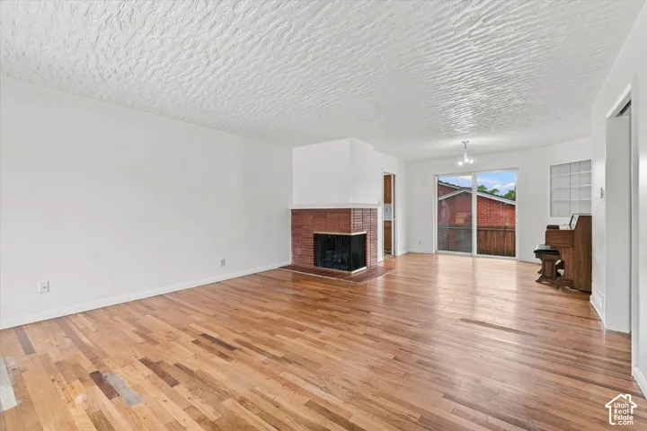 Hardwood flooring, brick fireplace surround, integrated fireplace insert, sliding glass doors, textured ceiling