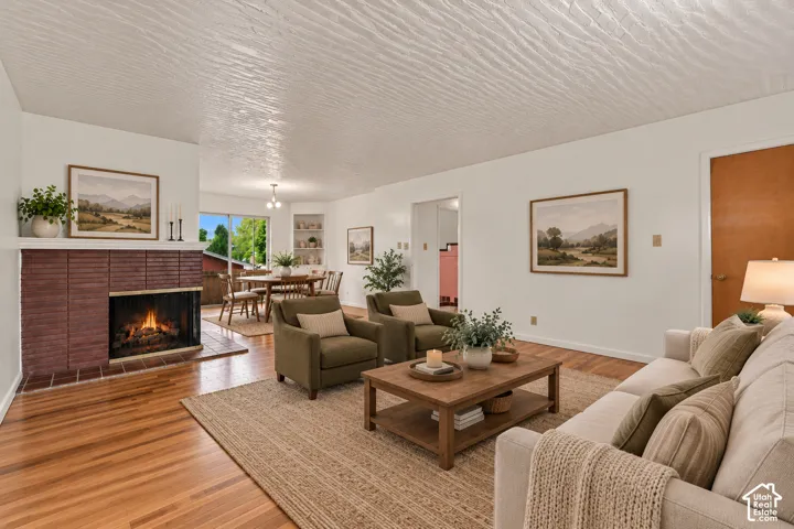Brick fireplace with hearth, wood-finish flooring, white walls, and built-in shelving