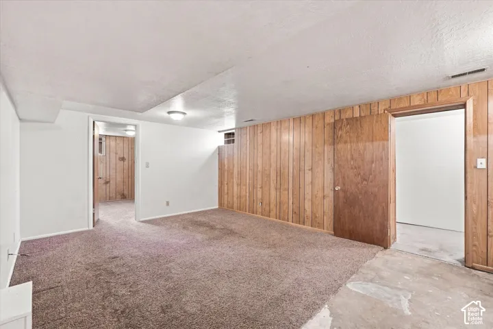 Carpeted flooring, wood paneling, flush mount lighting, painted walls, and an interior door
