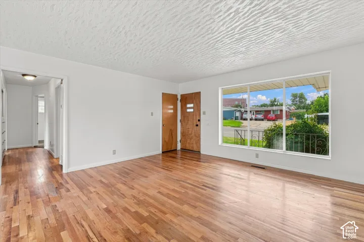Hardwood flooring, painted white walls, large picture window, and a wood-panel entry door