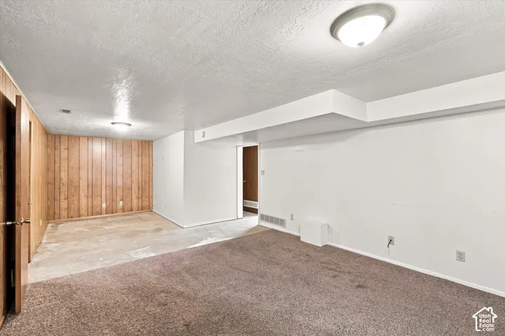 Expansive room featuring carpet flooring, wood paneling, and white painted walls