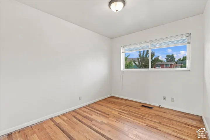 Hardwood flooring, white walls, and a semi-flush mount ceiling light