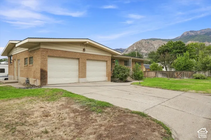 Brick exterior with a dual garage, concrete driveway, and mountain backdrop
