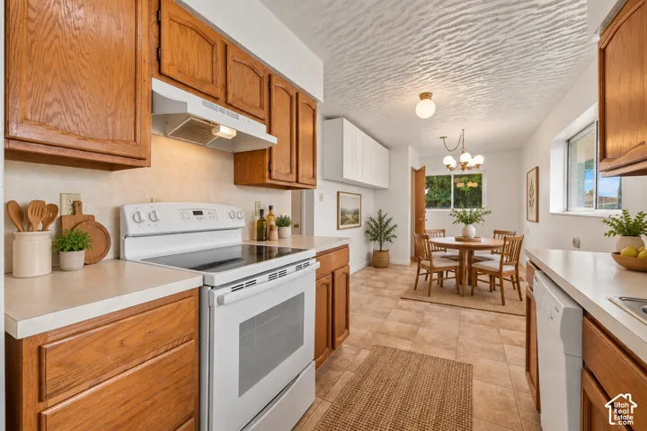 Kitchen featuring wood cabinetry, solid surface countertops, white appliances, and tiled flooring