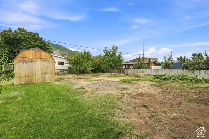 Expansive yard featuring a wooden shed, mature trees, and a wooden fence