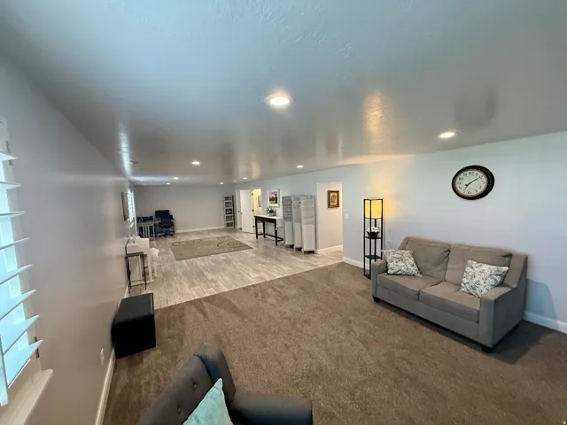 Spacious room featuring recessed lighting, a combination of wood-finish flooring and carpet, white plantation shutters, and light-toned walls