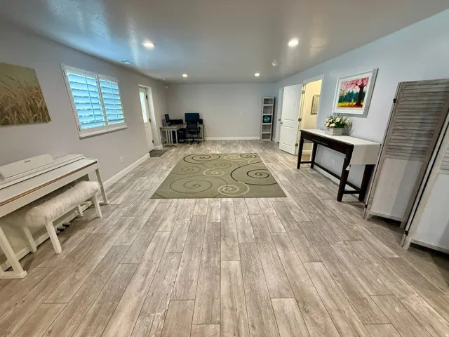 Expansive room featuring wood-finish flooring, recessed lighting, and white plantation shutters on windows