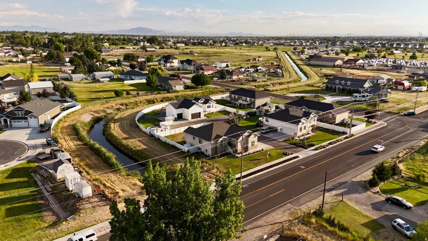 Aerial perspective showcasing residential properties with a mix of single-story and two-story homes, established landscaping, and a curvilinear waterway