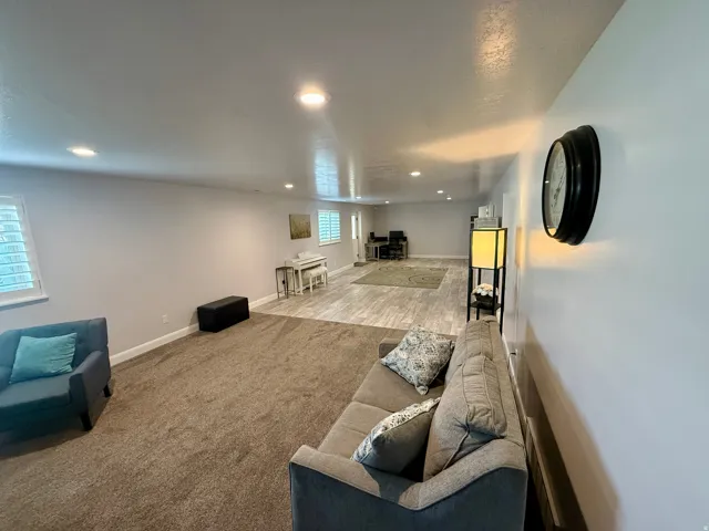 Spacious interior room featuring a blend of carpet and wood-finish flooring, recessed lighting, and window with plantation shutters