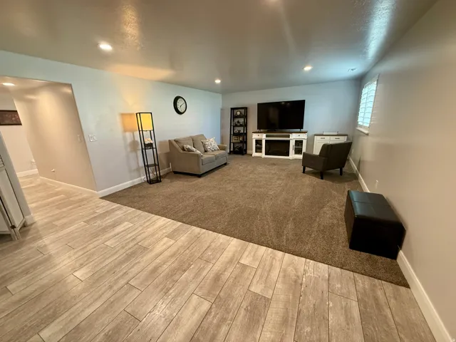 Spacious living area featuring recessed lighting, a built-in electric fireplace, wood-finish flooring, and plush carpeting