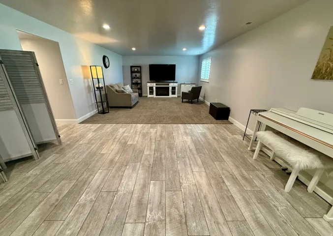 Spacious lower-level area featuring wood-finish flooring extending into a carpeted zone