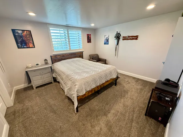 Carpeted interior room featuring recessed lighting, a window with white louvered shutters, and light-toned wall finishes