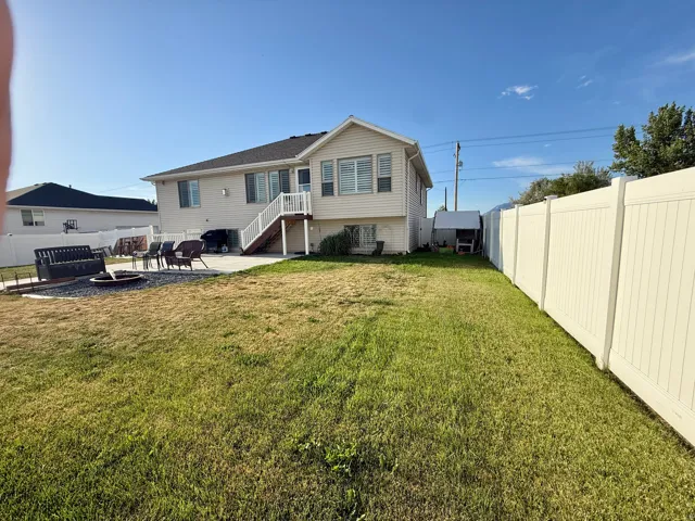 Expansive backyard featuring a large concrete patio, a dedicated fire pit area with stone surfacing, and a full privacy fence