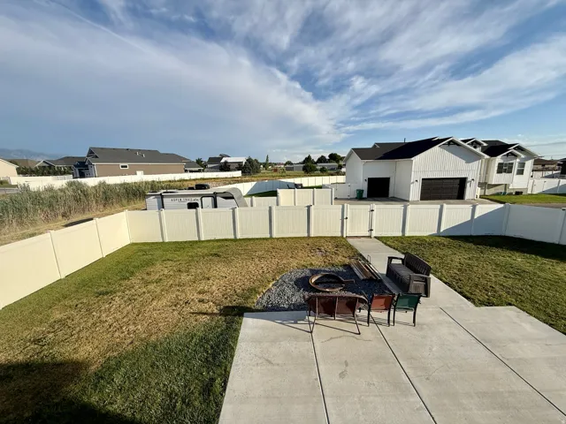 Expansive backyard featuring a concrete patio, a gravel seating area, and perimeter vinyl fencing
