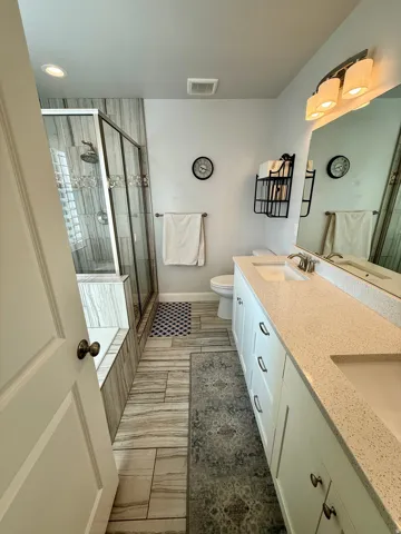 Bathroom featuring a double vanity with light-colored countertops, dual undermount sinks, and white cabinetry