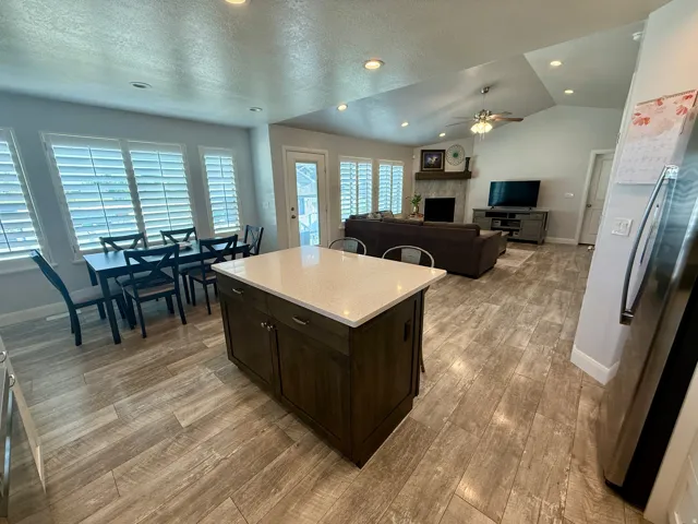 Kitchen island with light-toned countertop and dark wood-finish cabinetry, wood-look flooring, recessed lighting, and white plantation shutters