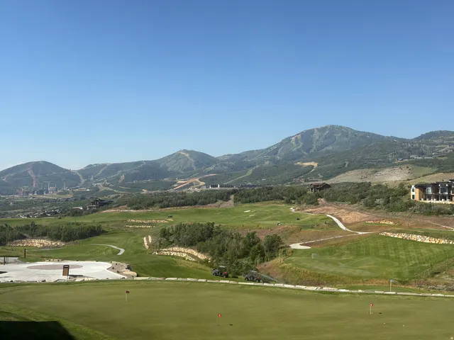 Expansive golf course setting featuring manicured greens and surrounding mountainous terrain