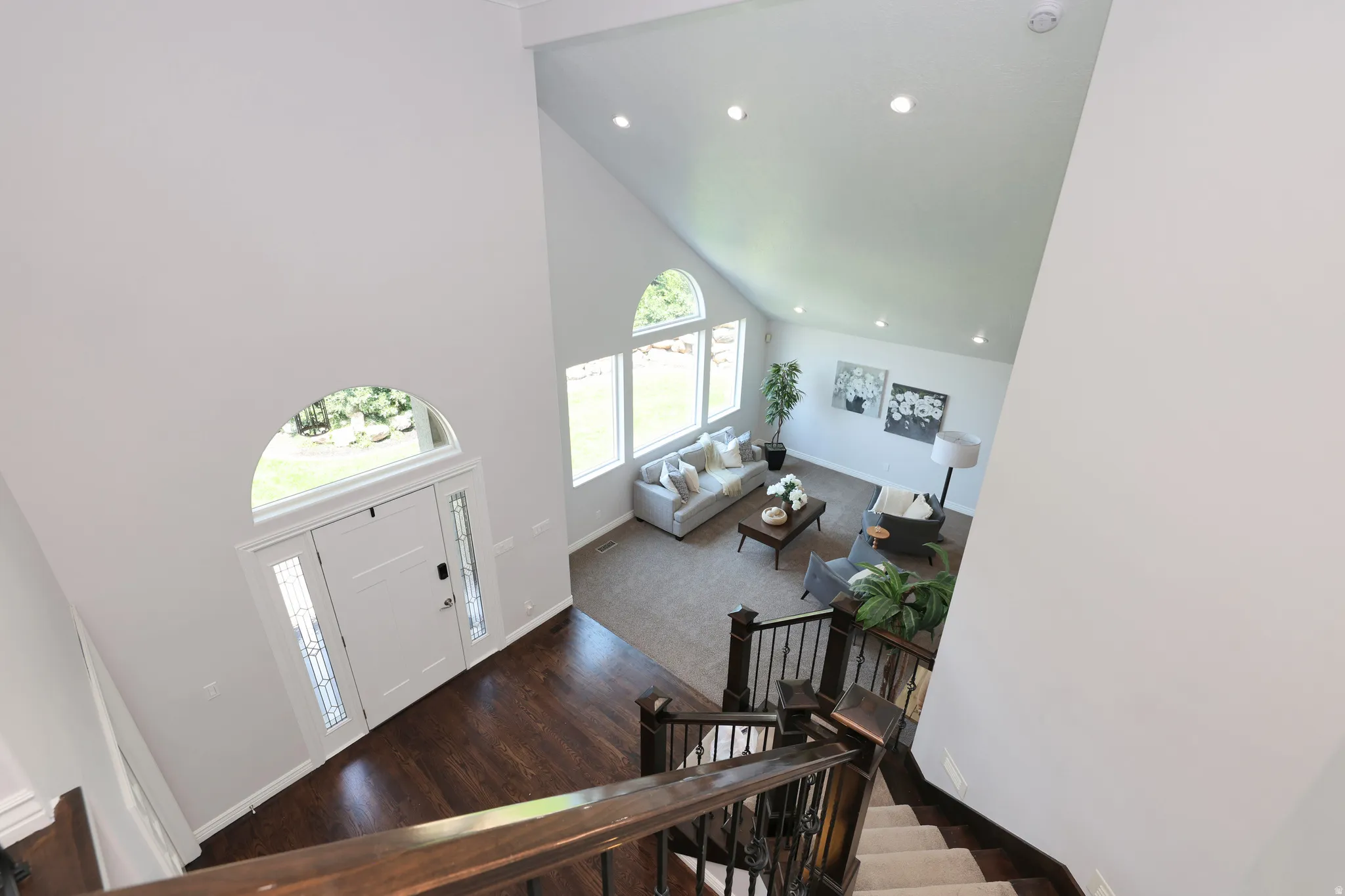 Two-story foyer with rich wood-finish flooring and an arched transom window above the entry door