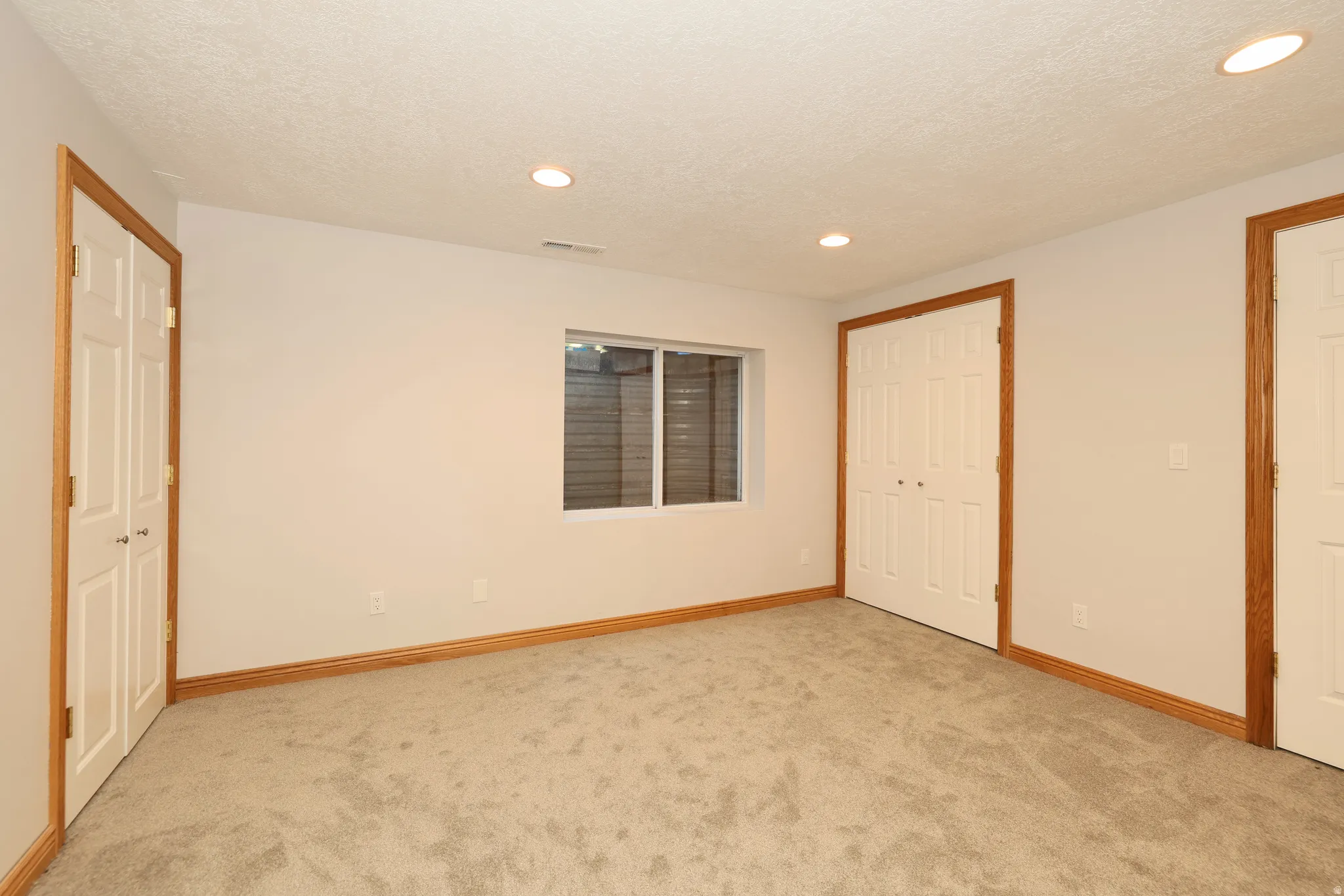 Carpeted room featuring white walls, wood trim, recessed lighting, and a window with blinds