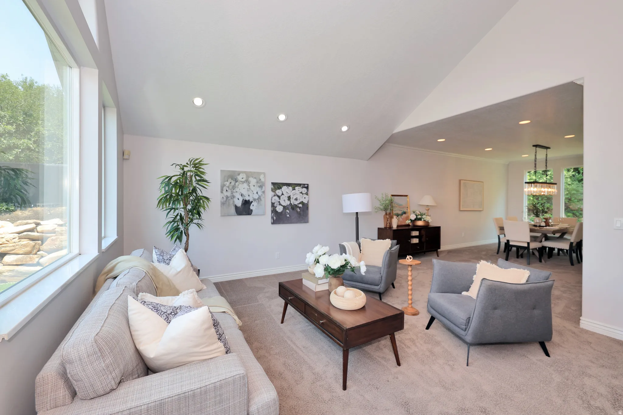 Spacious living area featuring high vaulted ceilings, recessed lighting, expansive windows, carpeted flooring, and an open layout connecting to the dining room