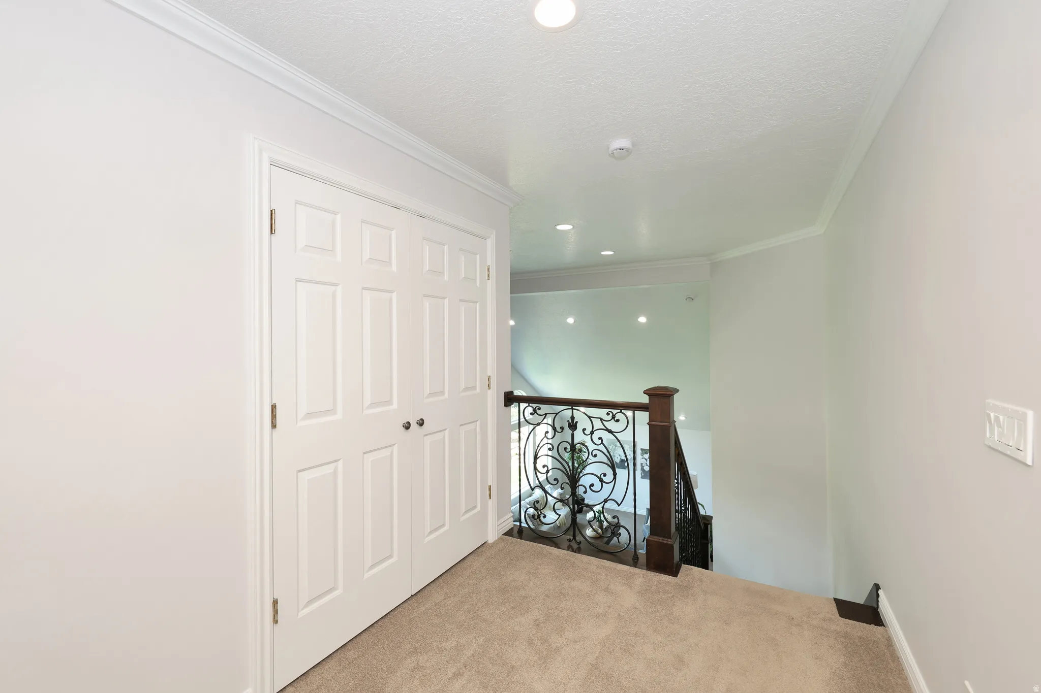 Upper landing with neutral carpeting, crown molding, and recessed lighting
