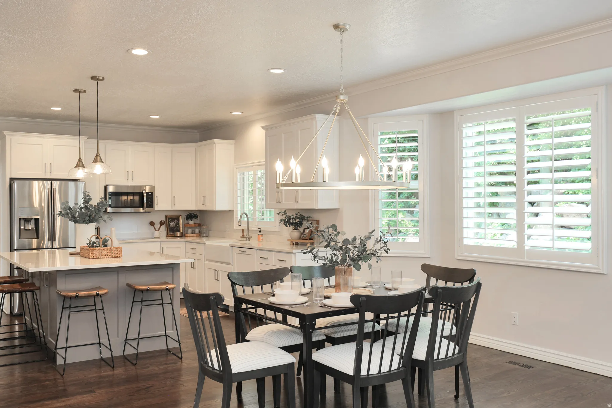 Spacious kitchen and dining area with white cabinetry, stainless steel appliances, a center island with bar seating, and wood-finish flooring