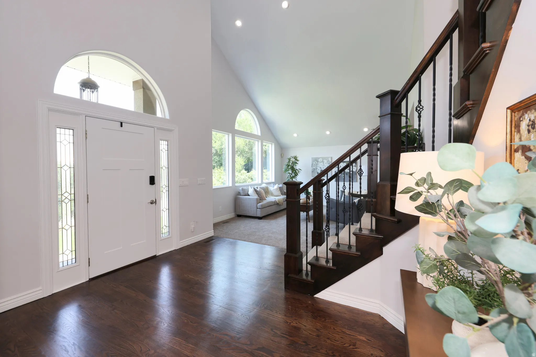 Grand entry featuring a white door with sidelights, an arched transom, and dark wood-finish flooring