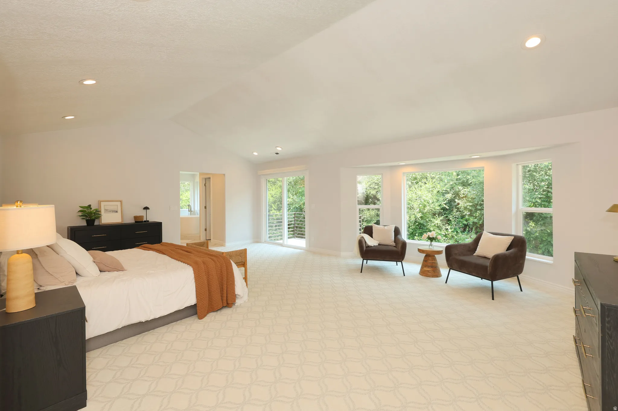 Expansive room featuring vaulted ceilings, recessed lighting, patterned carpeting, a large bay window, and sliding glass doors to a balcony