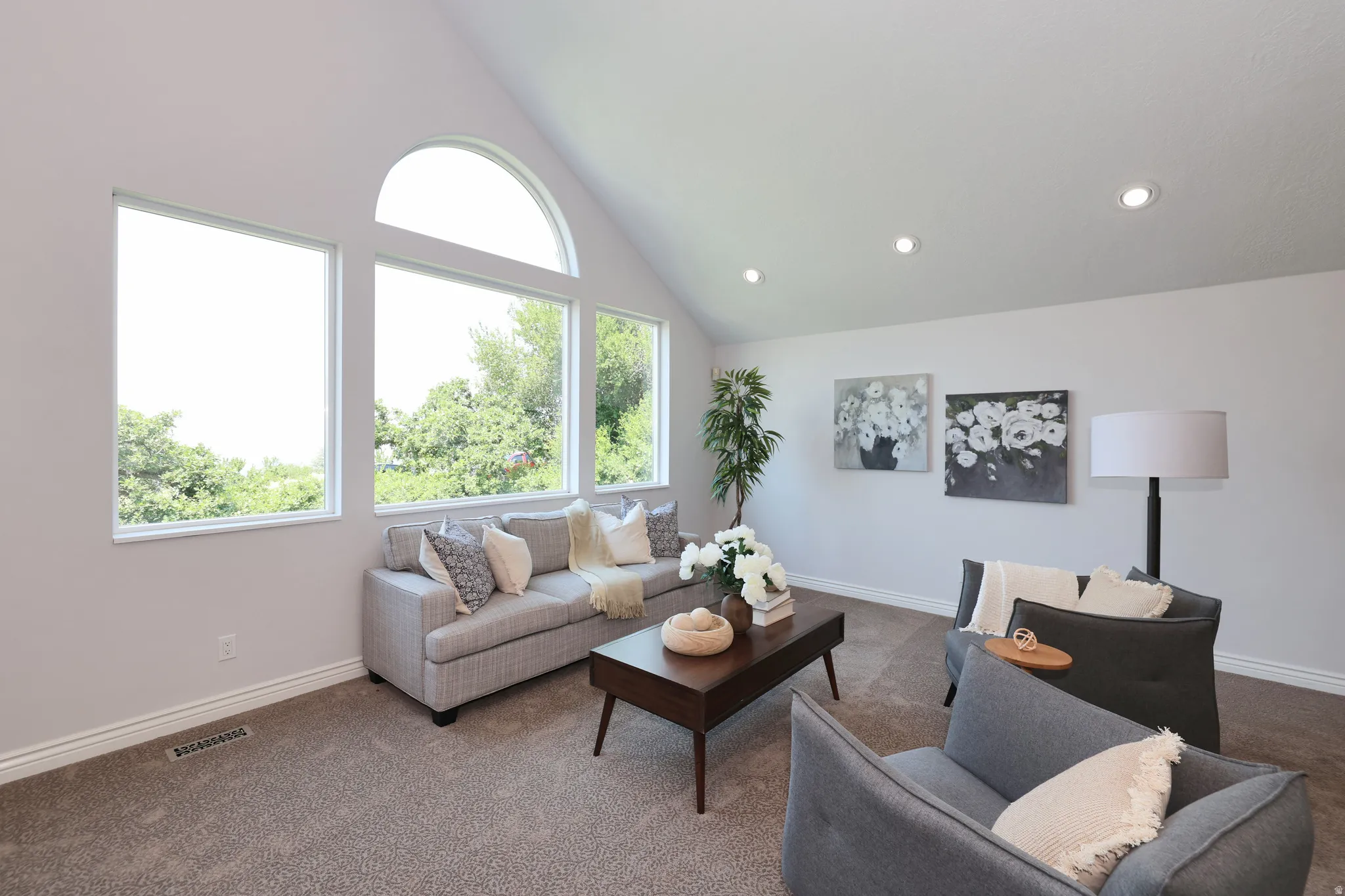 Vaulted ceiling living space featuring a wall of windows including an arch-top window, recessed lighting, and soft carpet flooring