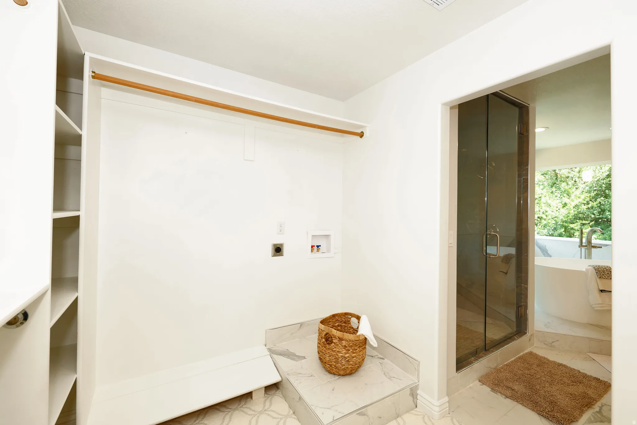 Integrated laundry area featuring plumbing connections for a washer and dryer, adjacent to a custom walk-in closet with built-in shelving and a clothing rod