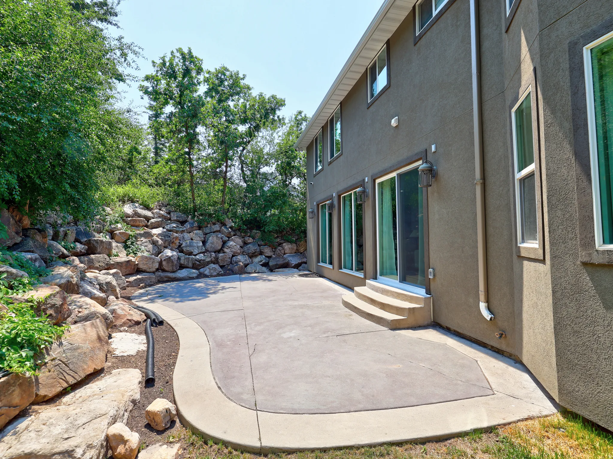 Expansive concrete patio bordered by natural rock landscaping, providing a private outdoor space