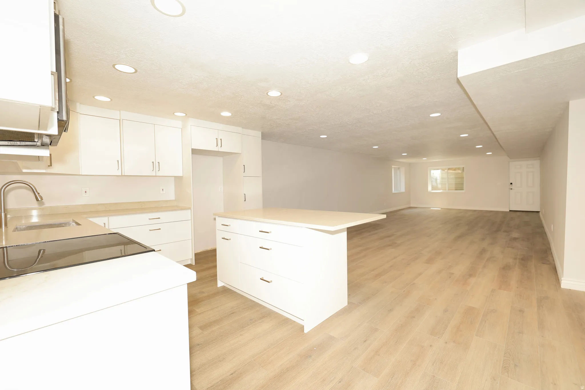 Open-concept living space featuring a modern kitchen with white cabinetry, light-toned countertops, and a central island