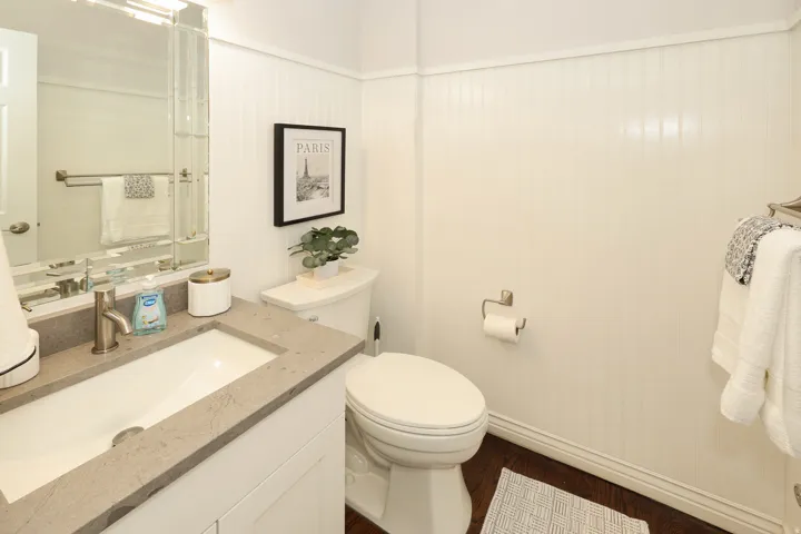 Bathroom featuring a single vanity with a rectangular basin, light-toned stone countertop, and brushed nickel faucet