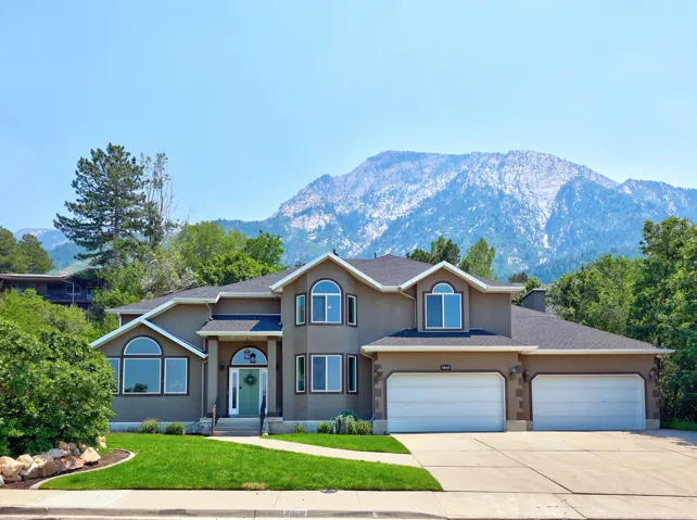 Stucco exterior residence featuring an arched entry, multiple arched windows, and a prominent mountain backdrop