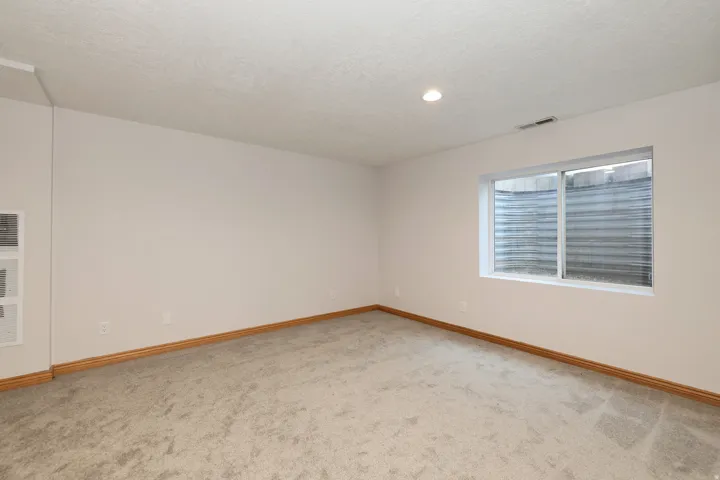 Bright interior space featuring light-toned walls, neutral carpet, and wood-finish baseboards