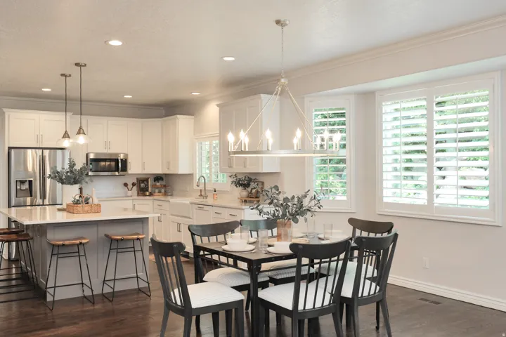 Spacious kitchen and dining area with white cabinetry, stainless steel appliances, a center island with bar seating, and wood-finish flooring