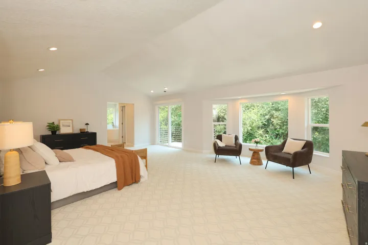 Expansive room featuring vaulted ceilings, recessed lighting, patterned carpeting, a large bay window, and sliding glass doors to a balcony