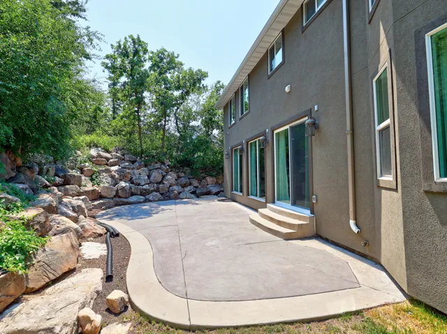 Expansive concrete patio bordered by natural rock landscaping, providing a private outdoor space