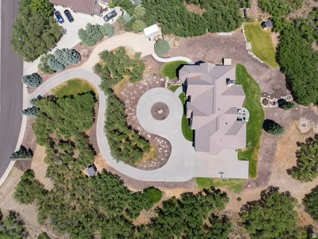 Estate property featuring an extensive private driveway, a circular motor court with a central landscape element, a multi-gabled roofline, and established natural landscaping