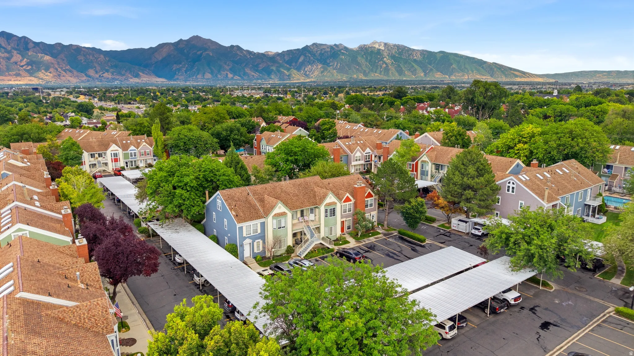 Community of multi-story residences with diverse exterior colors, featuring brown shingle roofing and mature trees