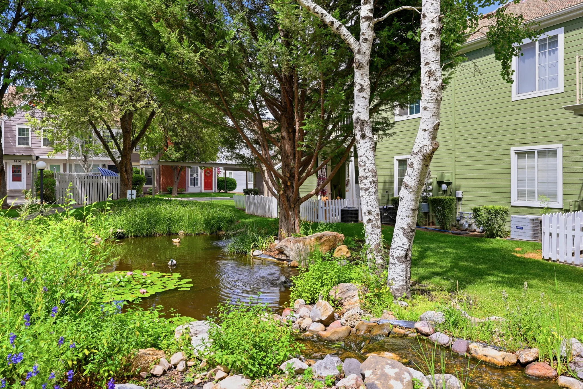 Landscaped grounds featuring a central pond with lily pads and a stream